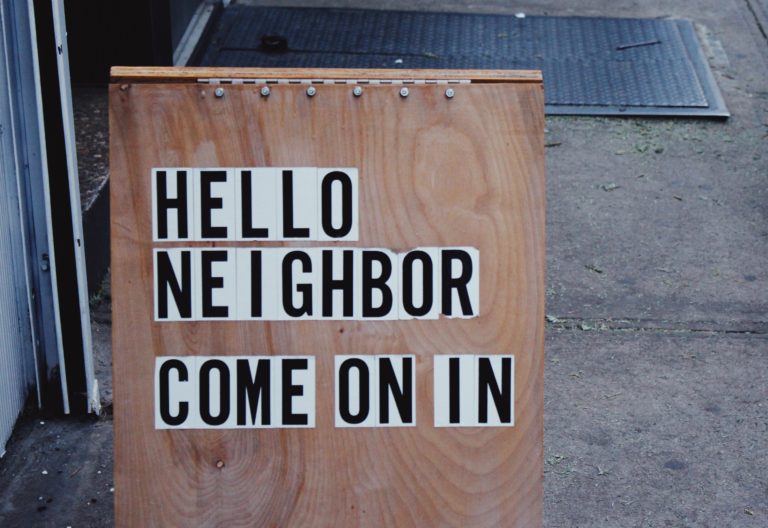 brown wooden board with HELLO NEIGHBOR COME ON IN signage